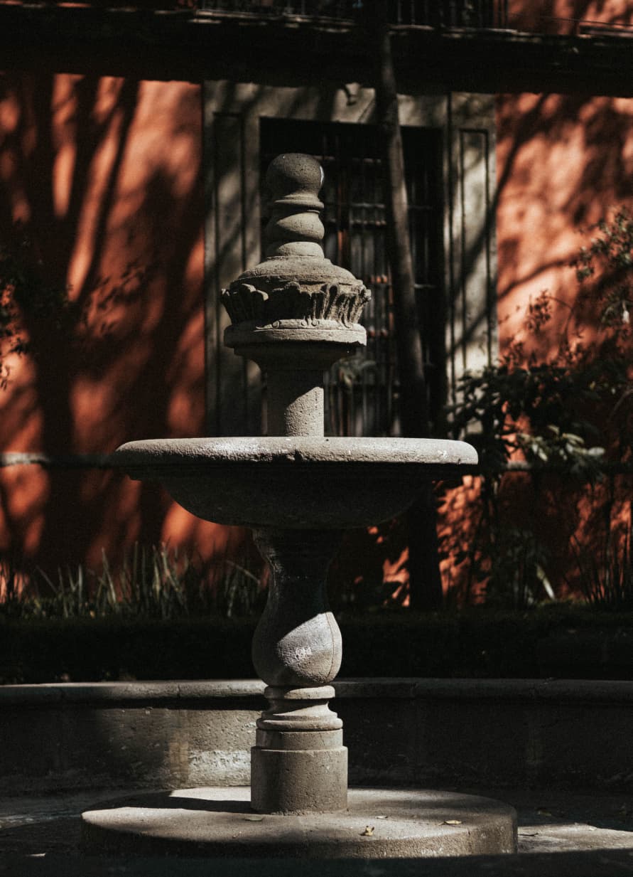 Fonte de pedra com sombras nas paredes vermelhas