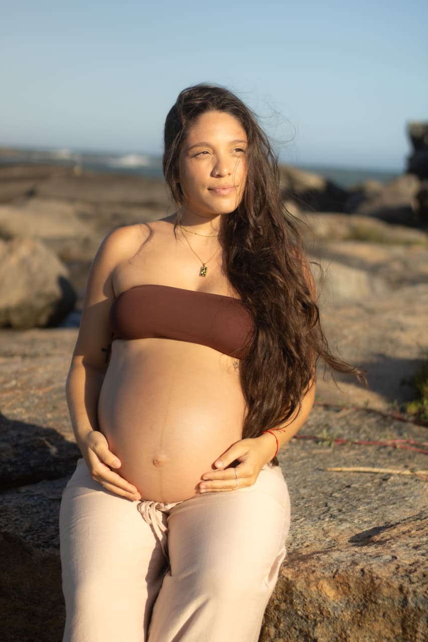 Monique sentada nas pedras, sozinha